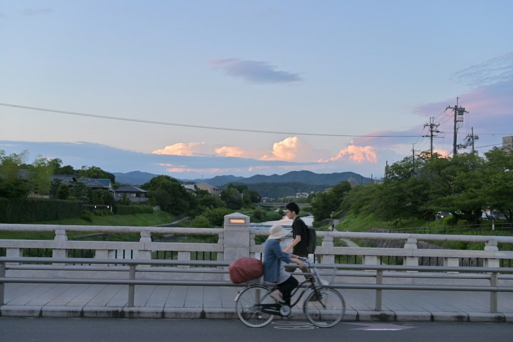 A man riding a bike down a street next to a bridge